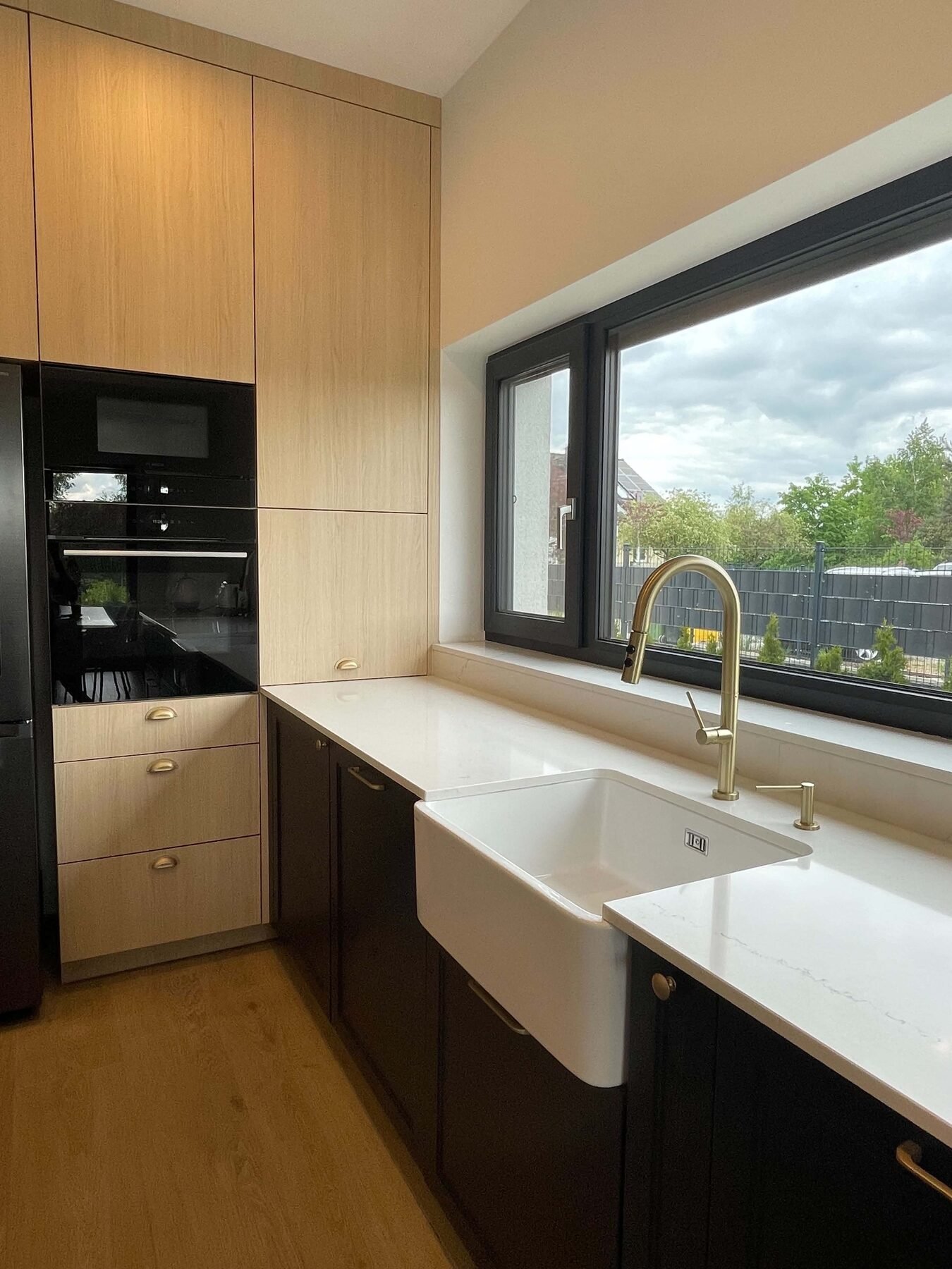 Blat pod oknem z Technistone Mistral White i ceramicznym zlewem farmhouse